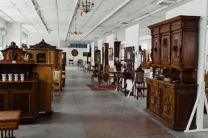 A spacious showroom filled with various antique wooden furniture pieces on display.